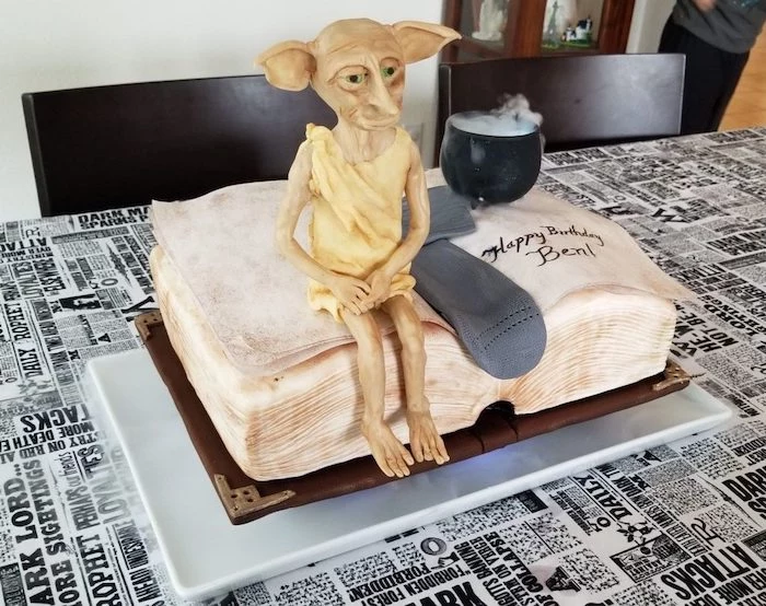hogwarts cake, cake in the shape of open book, grey sock and dobby made of fondant, placed on top