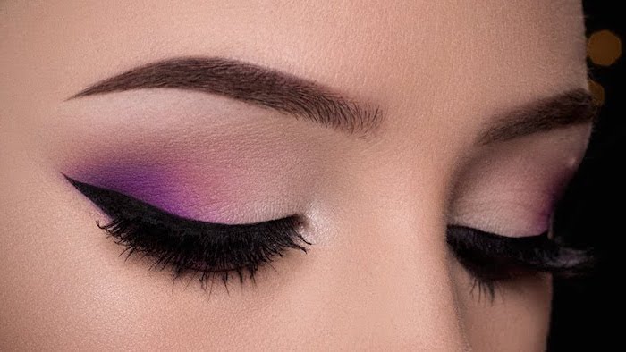 nude and dark pink eyeshadow colors, black cat eyeliner, makeup for beginners, woman with dark eyebrows