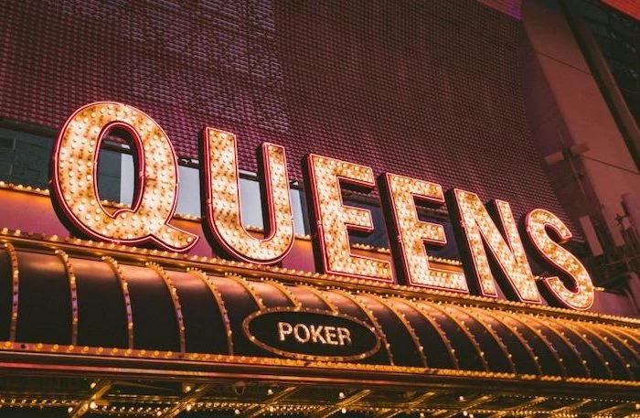 queens and poker signs with led lights, aesthetic backgrounds, placed over the entrance of a casino