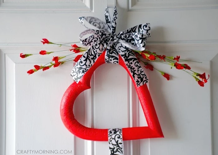 red foam heart tied with black and white satin ribbon, heart decorations, faux red flowers on top, hanging on white door