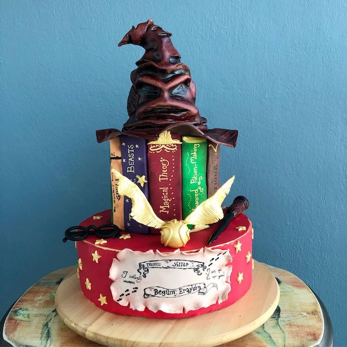 two tier cake made with fondant, sorting hat on top, hogwarts cake, placed on wooden tray, blue background