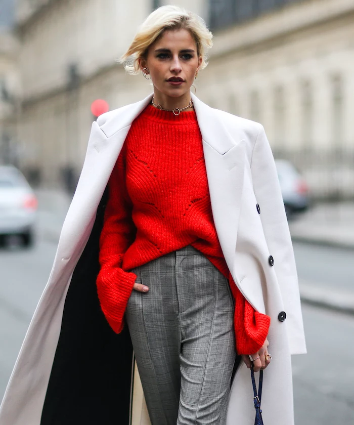 blonde woman wearing red sweater, grey pants and long white coat, valentine's day clothes, walking on the street