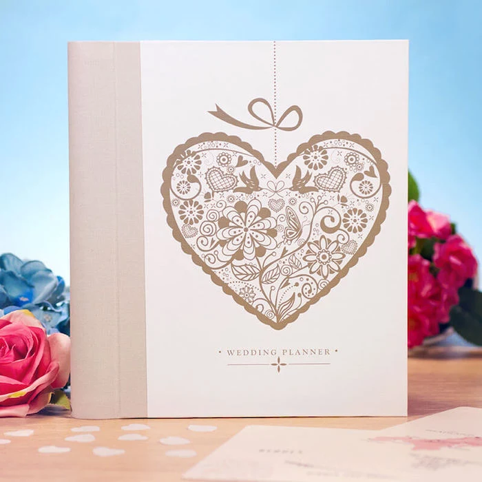 wedding planner with beautiful front cover, valentine day gifts for girlfriend, placed on a wooden surface, flowers around it