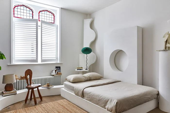bedroom with single bed, antique stained glass windows, wooden floors and white walls, small wooden chair