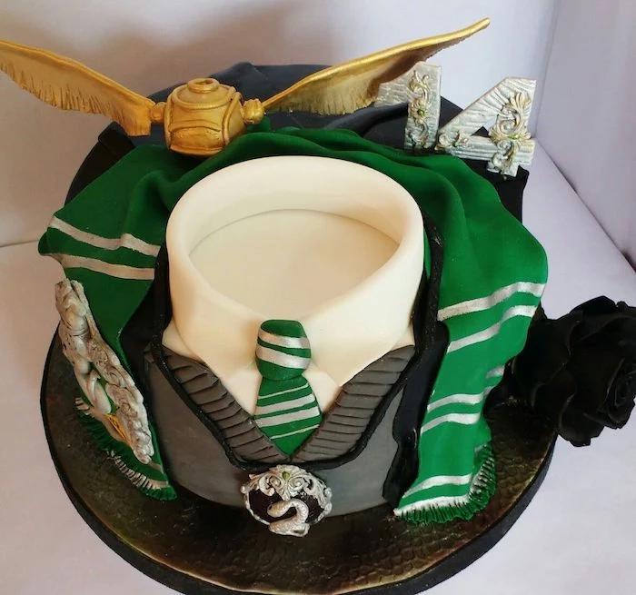 one tier slytherin uniform cake, hogwarts cake, golden snitch on top, green and silver scarf made of fondant around it