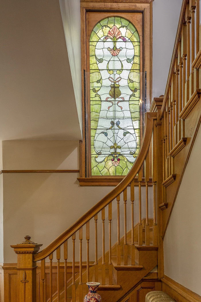 wooden staircase and white walls, stained glass window panels, window between the floor decorated with colored glass