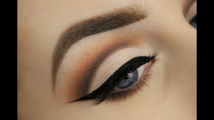 woman with blue eyes, thick light brown eyebrows, nude eyeshadow look, black cat eyeliner