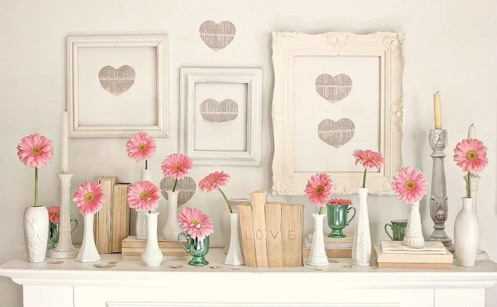 three vintage wooden frames, posters of hearts inside, valentine table decorations, pink flowers in separate vases