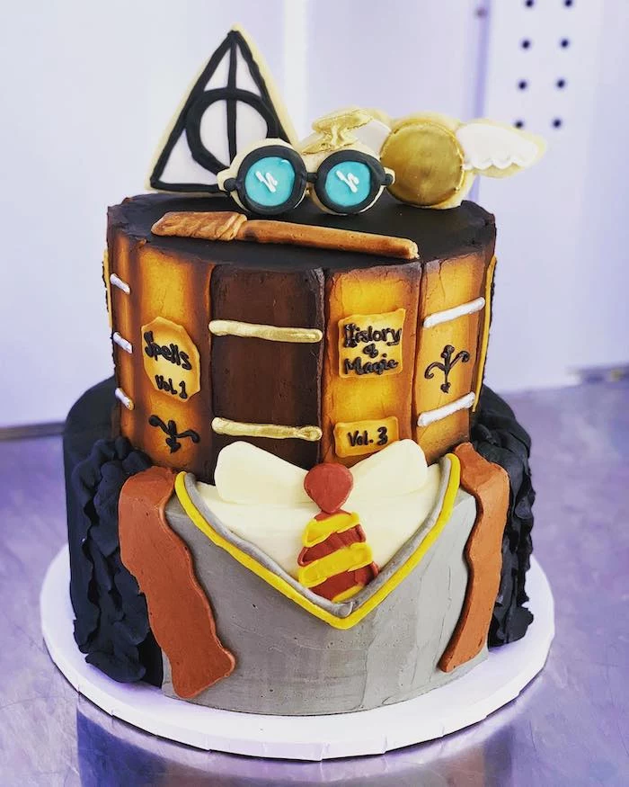 two tier gryffindor cake, harry potter birthday cake hagrid, gryffindor uniform bottom layer, glasses wand snitch on top