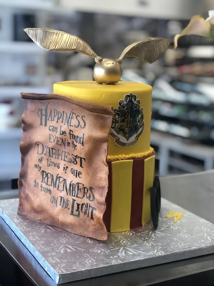 two tier gryffindor cake, made with yellow and red fondant, golden snitch on top, harry potter birthday cake hagrid