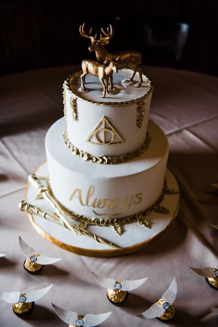 two tier cake made with white fondant, gold decorations, harry potter birthday cake hagrid, stag and deer patronus toppers