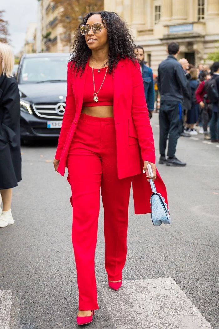 woman walking down the street, wearing red suit with crop top, valentines day outfit girl, red heels and blue bag