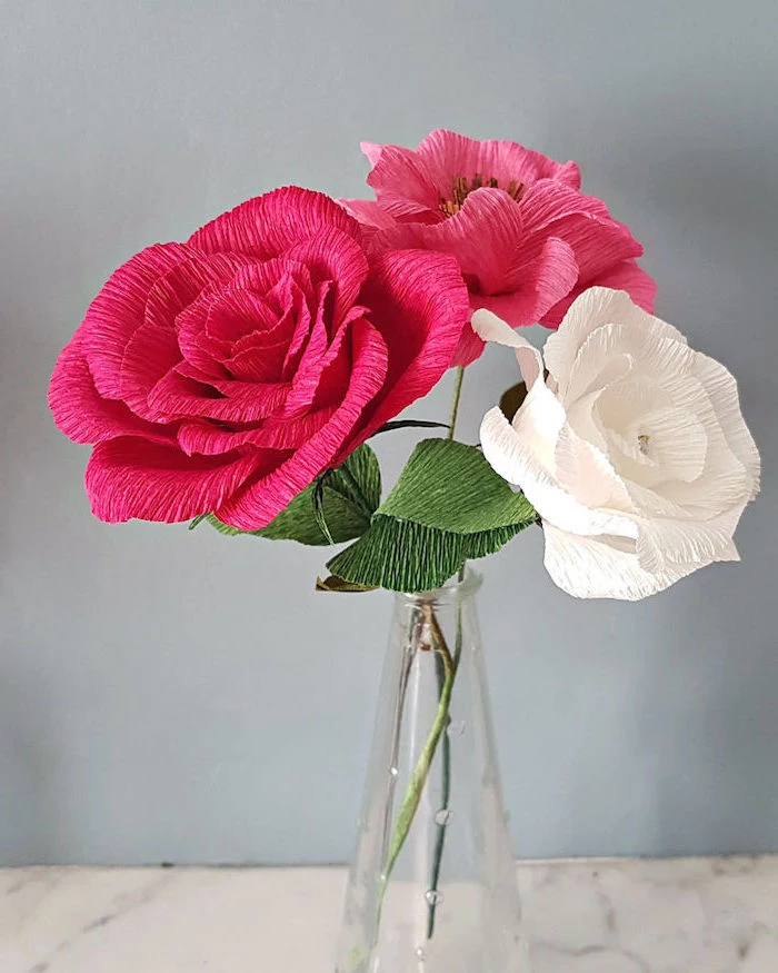 white and pink roses made of crepe paper, arranged as a bouquet, giant paper flower template, placed in small glass vase