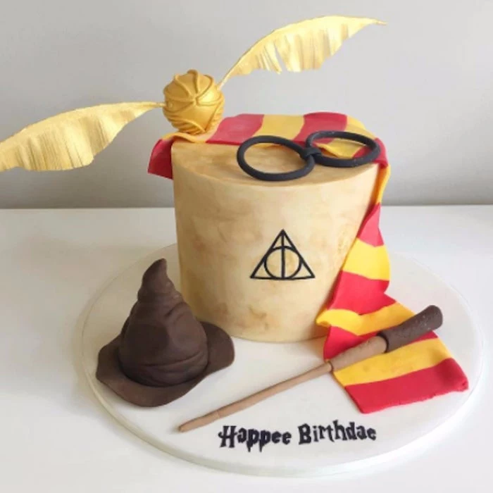 harry potter birthday cake ideas, one tier cake, gryffindor scarf made of red and yellow fondant, wand and snitch