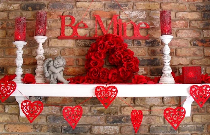be mine banner, red hearts garland, vintage candlesticks, arranged on white shelf, valentine day table decorations, brick wall