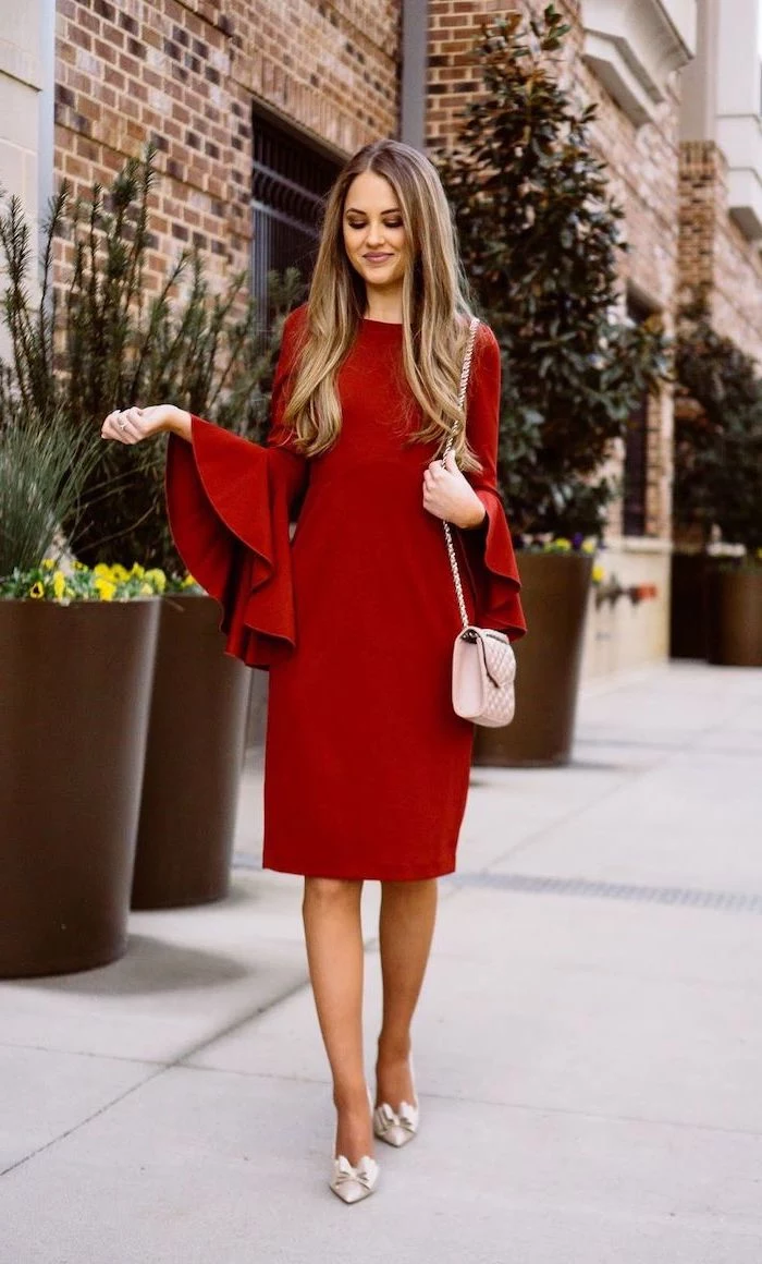 woman walking on sidewalk, wearing red dress with wide ruffled sleeves, valentines day outfit ideas, pink bag
