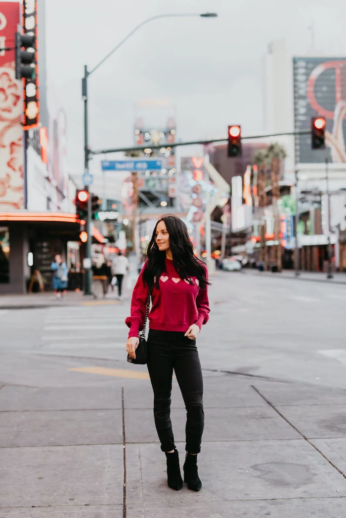 woman standing on sidewalk, wearing pink blouse, cute valentines day outfits, black pants and black velvet boots
