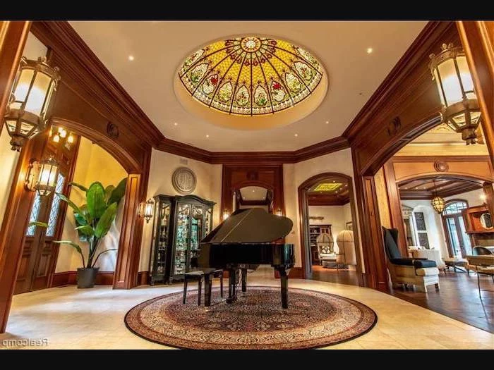 hallway with piano in the middle, wooden door frames, ceiling window, custom stained glass windows, white tiled floor