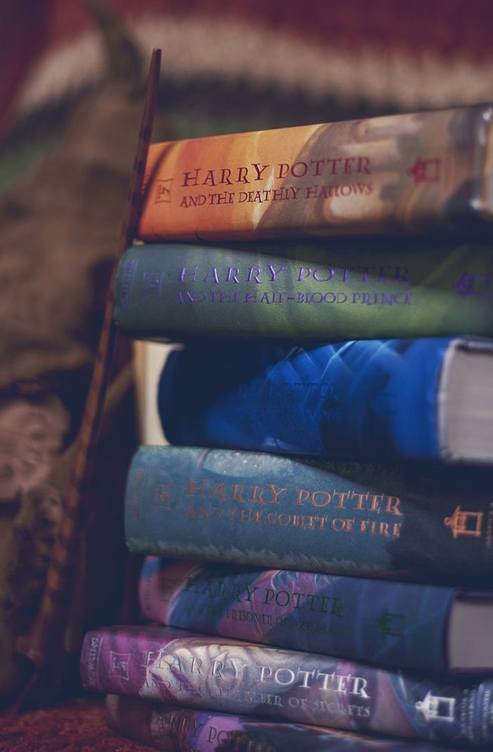 hogwarts wallpaper, all seven books, stacked together, wooden wand next to them