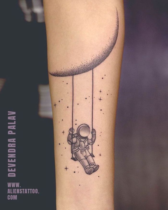 forearm tattoo, astronaut swinging on a swing, hanging from the moon, black and white tattoo, galaxy tattoo
