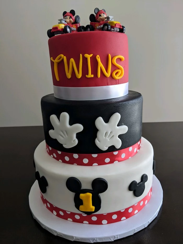 three tier cake, covered with red black and white fondant, mickey mouse cake, decorated with two cake toppers