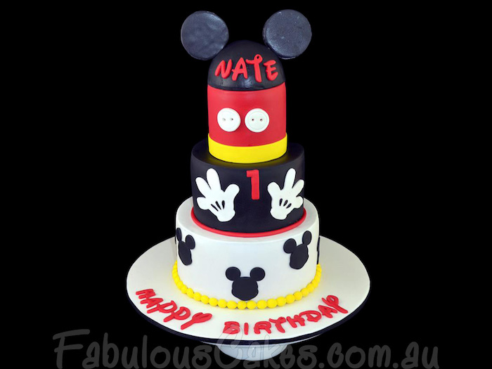 four tier cake, covered with black red white yellow fondant, mickey mouse cake, placed on white cake stand