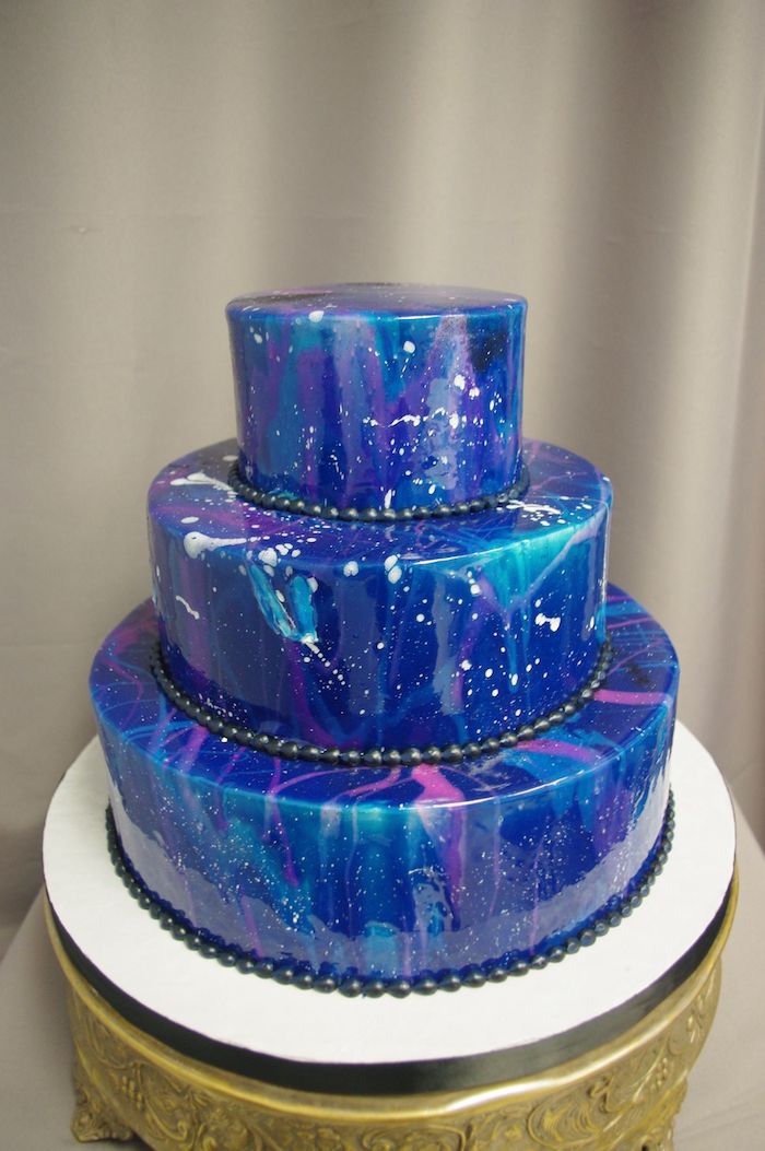 three tier cake, galaxy cake, blue pink and turquoise mirror glaze, placed on white and gold cake tray