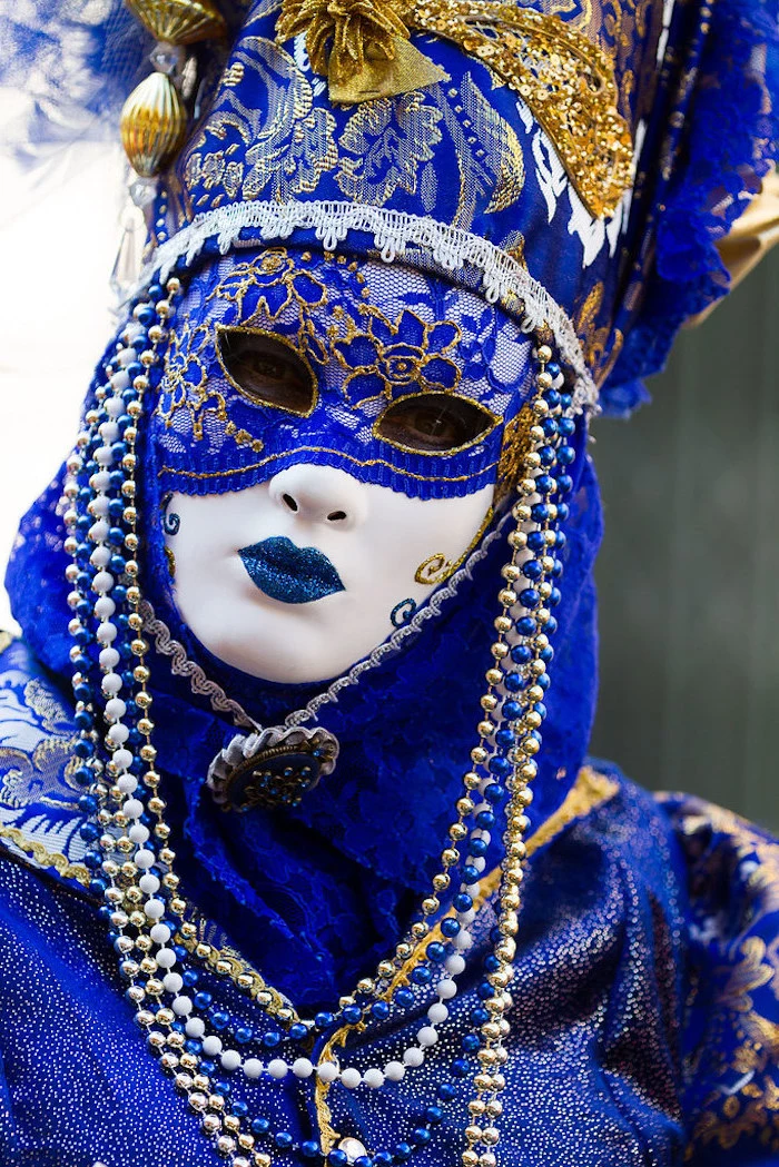 blue white and gold mask, mardi gras mask, decorated with blue and gold lace, blue and gold beads around it