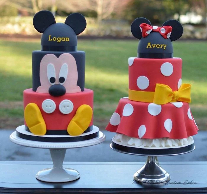 two three tier cakes, covered with black white and red fondant, mickey mouse 1st birthday cake, placed on white cake stands