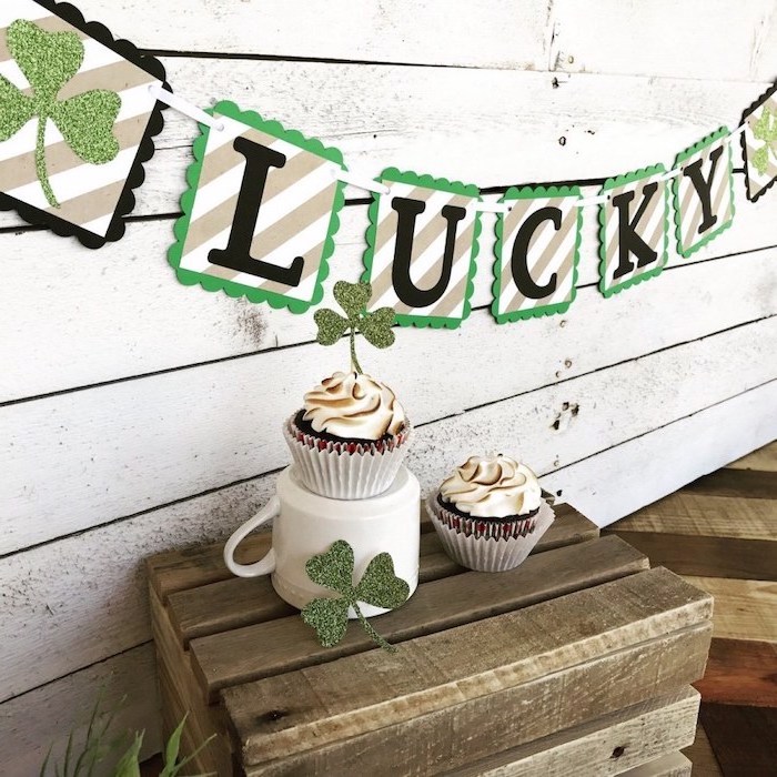 cupcakes with shamrock toppers, placed on wooden cupboard , st patrick's day decorations, lucky paper garland