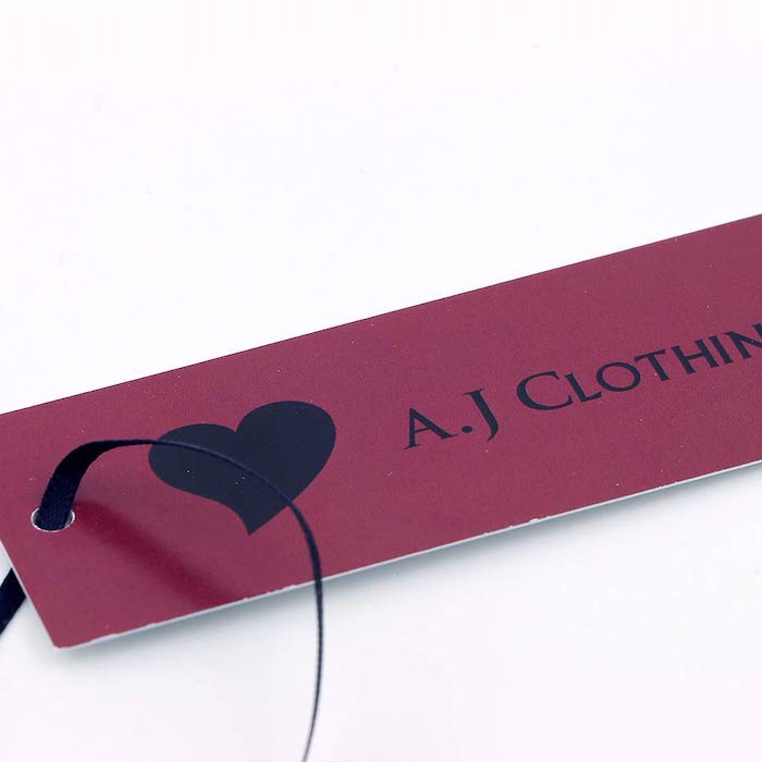 dark red clothing tag, aj clothing written in black with black heart on the side, white background, clothing labels