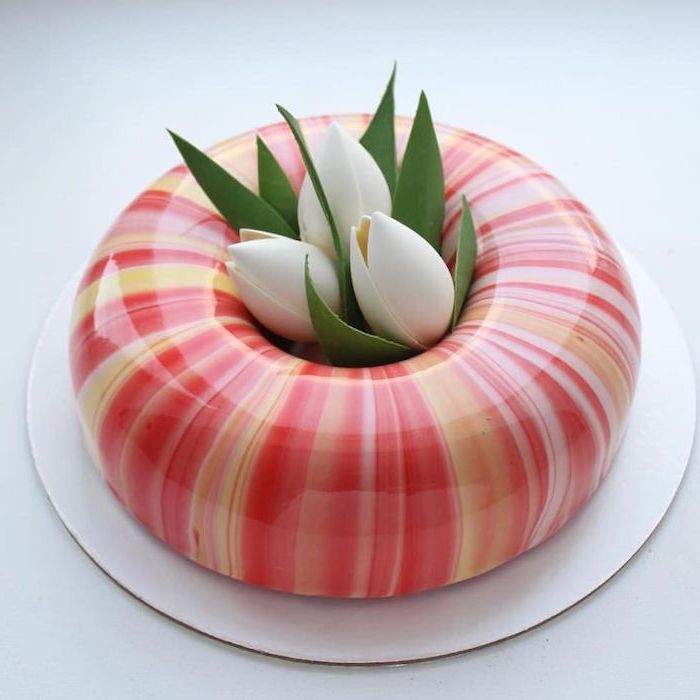 donut cake covered with orange and yellow glaze, cake glaze recipe, white tulips in the middle, placed on white cake tray
