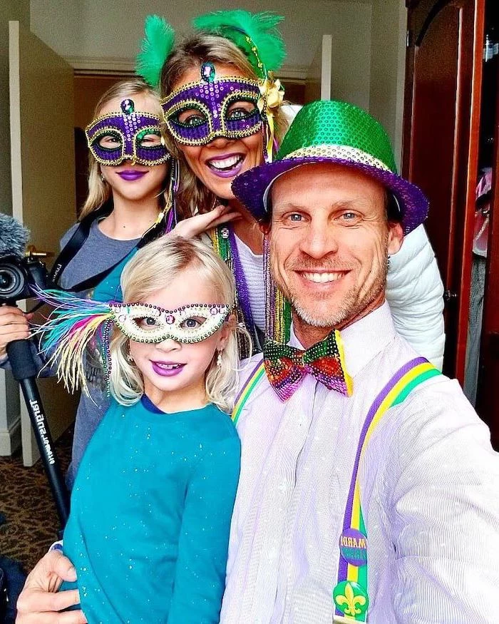 family man and woman with their two daughters, black masquerade mask, wearing masks and hats in purple gold and green