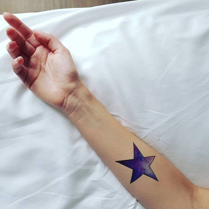 forearm tattoo on female hand, leaning on white surface, universe tattoo, star with galaxy inside it