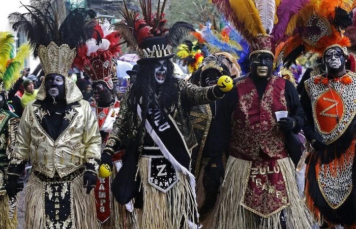 four men dressed in different costumes, wearing large hats with colorful feathers, gold masquerade mask