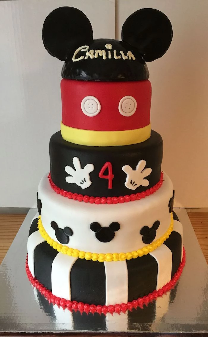 mickey cake, five tier cake, covered with white and black, yellow and red fondant, placed on silver cake tray