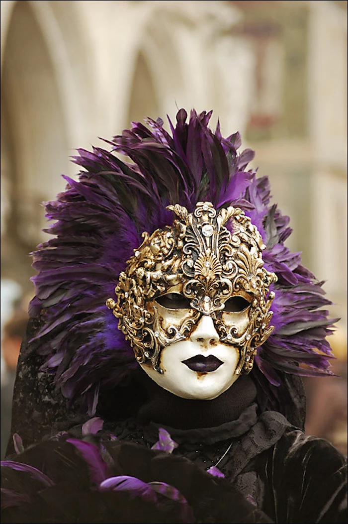 woman wearing white and gold mask, decorated with large black and purple feathers, gold masquerade mask