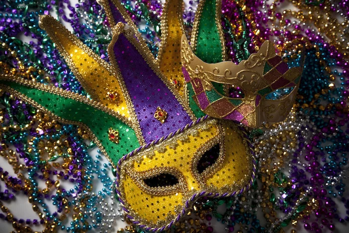 two masks in gold purple and green, decorated with glitter and rhinestones, masquerade masks for men, lots of beads necklaces