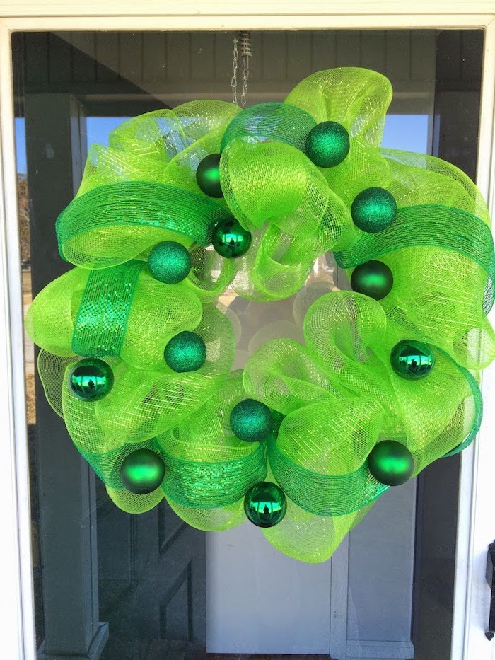wreath made with green tulle, decorated with green glitter baubles, st patrick's day party, hanging on glass door