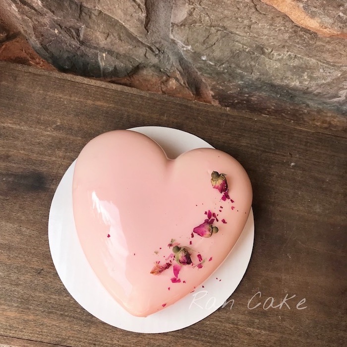 heart shaped one tier cake, covered with pink glaze, chocolate mirror glaze, flower decorations on top