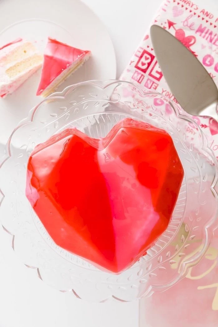 heart shaped one tier mini cake, covered with red mirror glaze, how to make glaze for cake, placed on glass cake stand