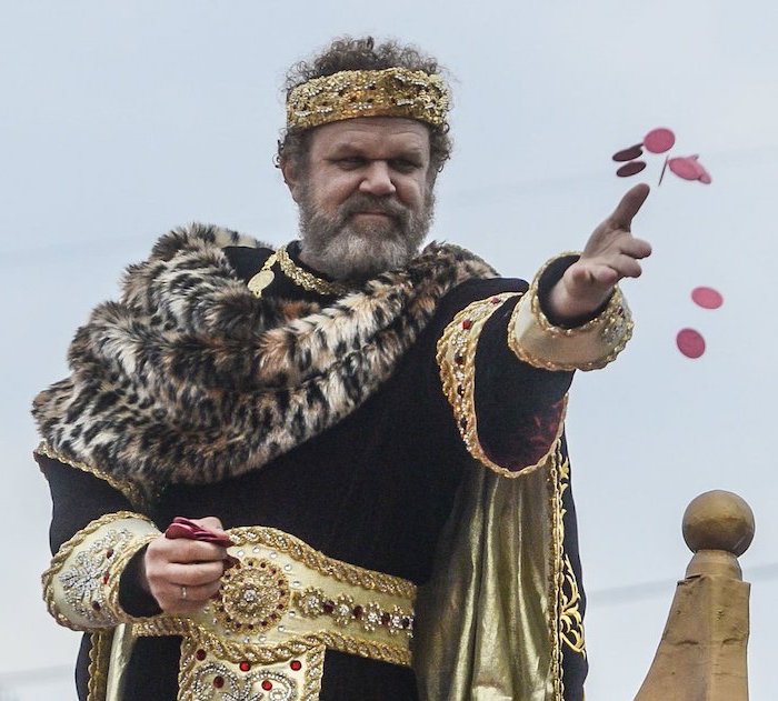 john c riley as king bacchus, masquerade masks, wearing black and gold costume, crown on his head