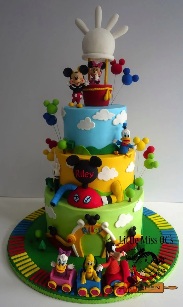 three tier cake, mickey mouse cake ideas, covered with blue yellow and green fondant, disney characters decorations