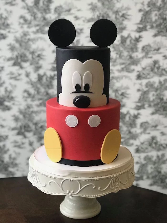 two tier cake, covered with black white and red fondant, mickey mouse cake ideas, placed on white cake stand
