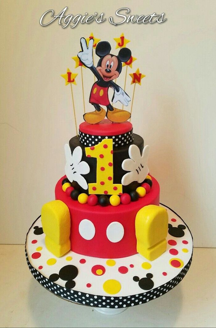two tier cake, covered with red and black fondant, mickey mouse cakes 1st birthday, placed on white cake stand