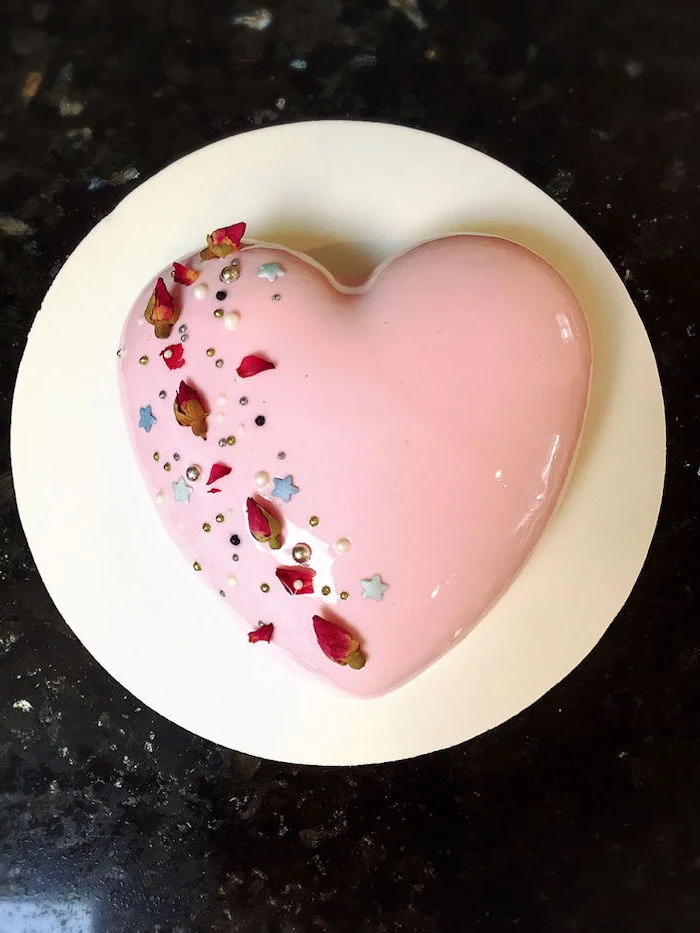 heart shaped one tier cake, covered with pink glaze, flowers and sprinkles on top, mirror glaze cake recipe, placed on white tray