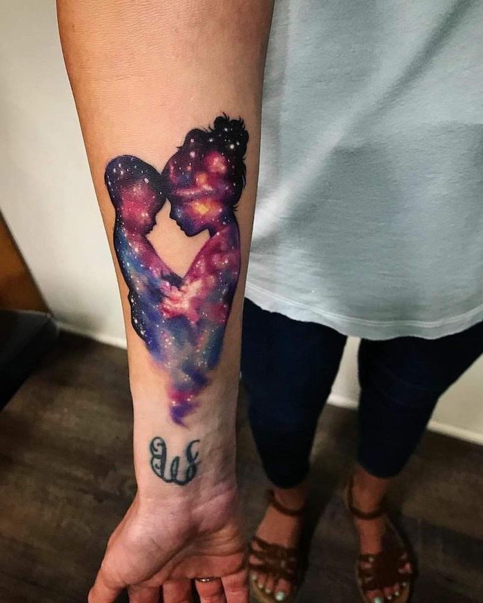 forearm tattoo on woman wearing white top, mom holding her son, galaxy inside the silhouettes, small space tattoos