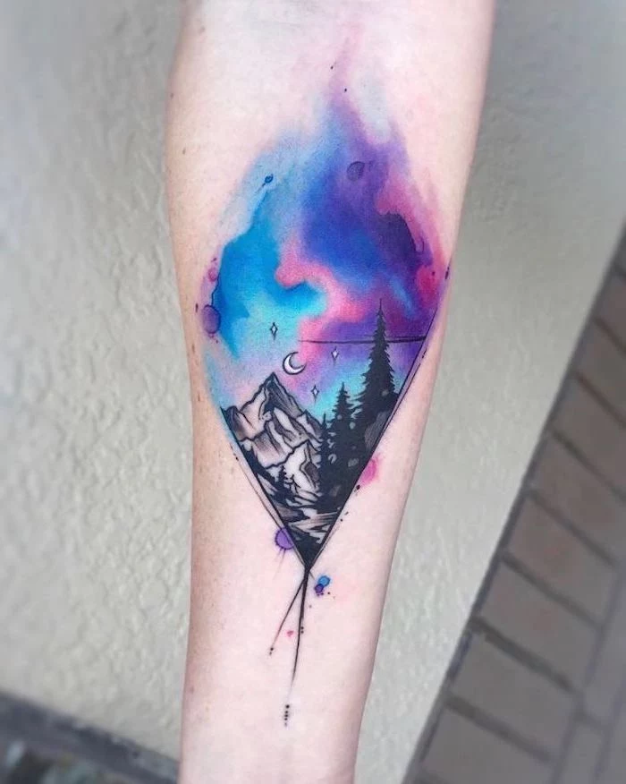 watercolor forearm tattoo, mountain landscape with tall trees, blue pink and purple galaxy above, small space tattoos
