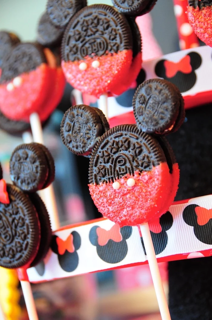 cake pops made of oreos, dipped in red chocolate, mickey mouse smash cake, arranged together on a stand