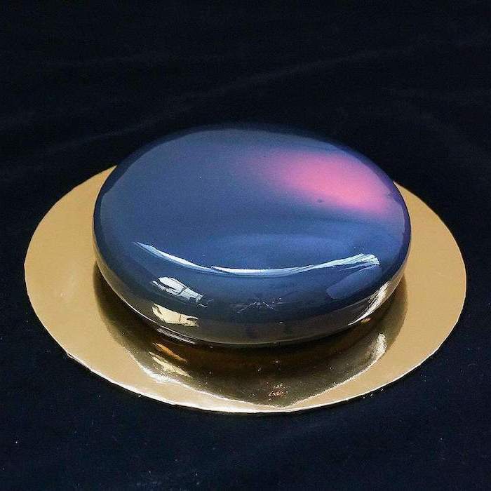 galaxy mirror cake, one tier cake covered with blue and pink glaze, placed on gold tray, placed on black surface